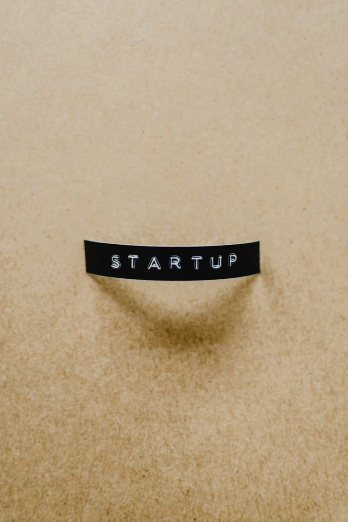 A minimalist image of the word 'STARTUP' on a beige textured surface conveying creative business concepts.